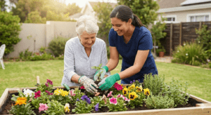 A caregiver and a senior woman smiling while planting flowers in a raised garden bed in Apex, NC, showcasing active companion care.