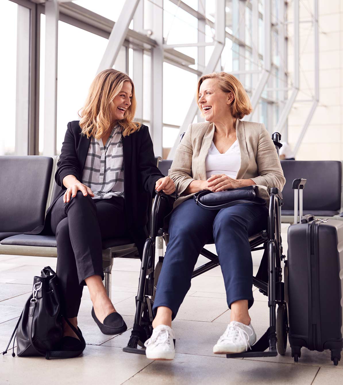 A caregiver sits in an airport with a client in a wheelchair
