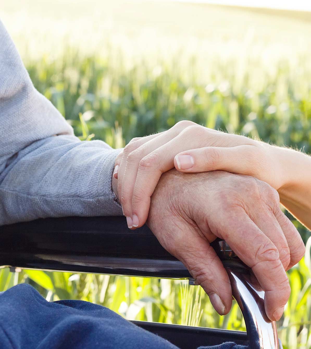 A caregiver holds the hand o a client in a wheelchair
