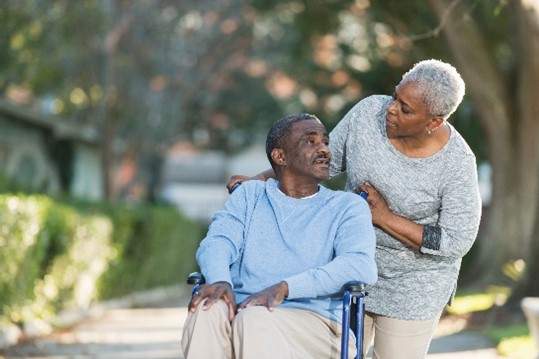 woman pushing man in wheelchair