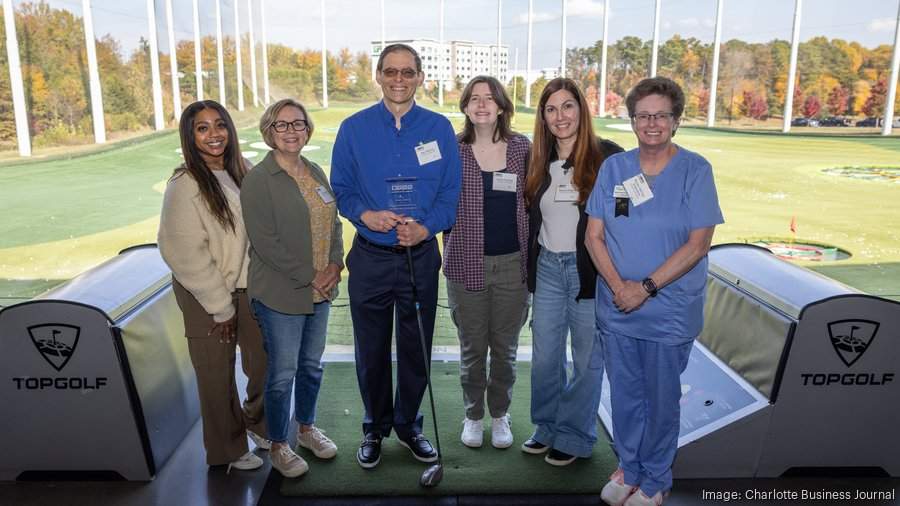 people standing together holding a trophy at Top Golf