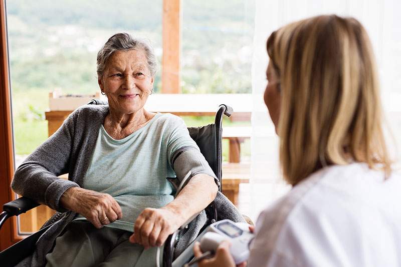 A caregiver speaks with a woman in a wheelchair