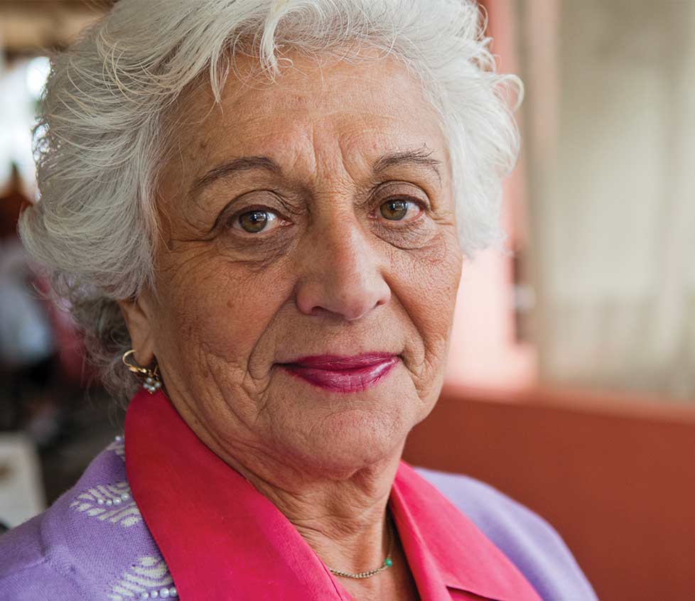 A senior woman sits in a chair in her living room