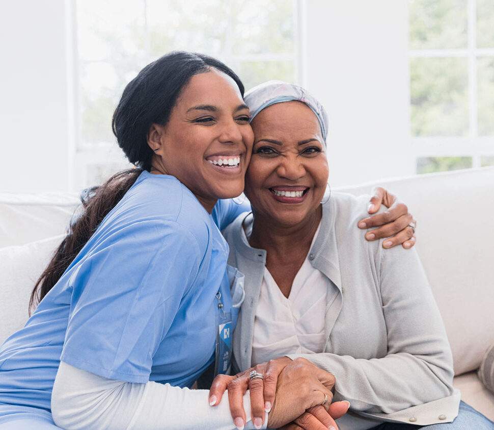 A caregiver sites with a client and gives her a hug