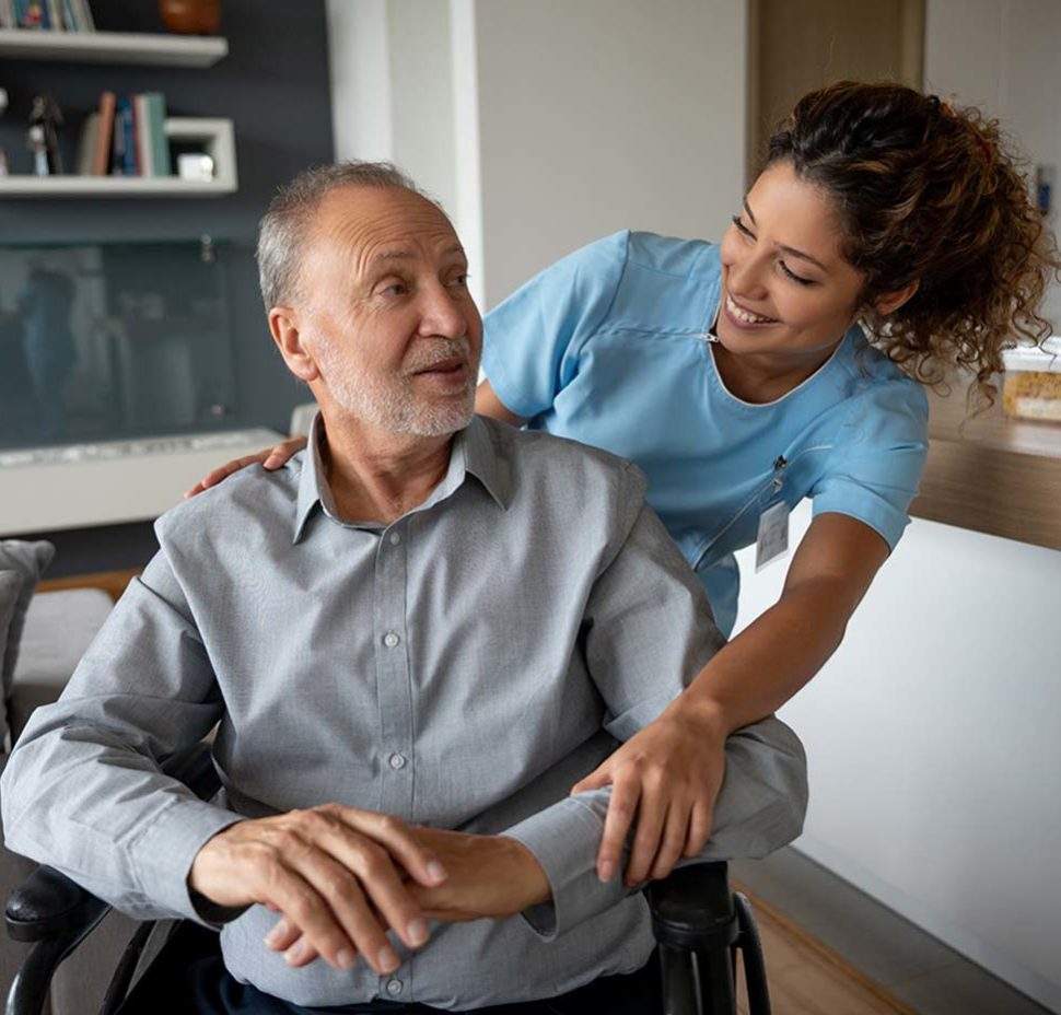 Caretaker resting arms onto man in wheelchair and smiling