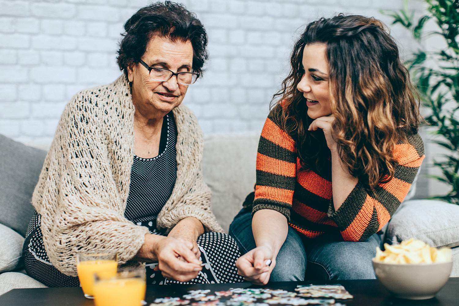 Two women sitting putting puzzle together at table