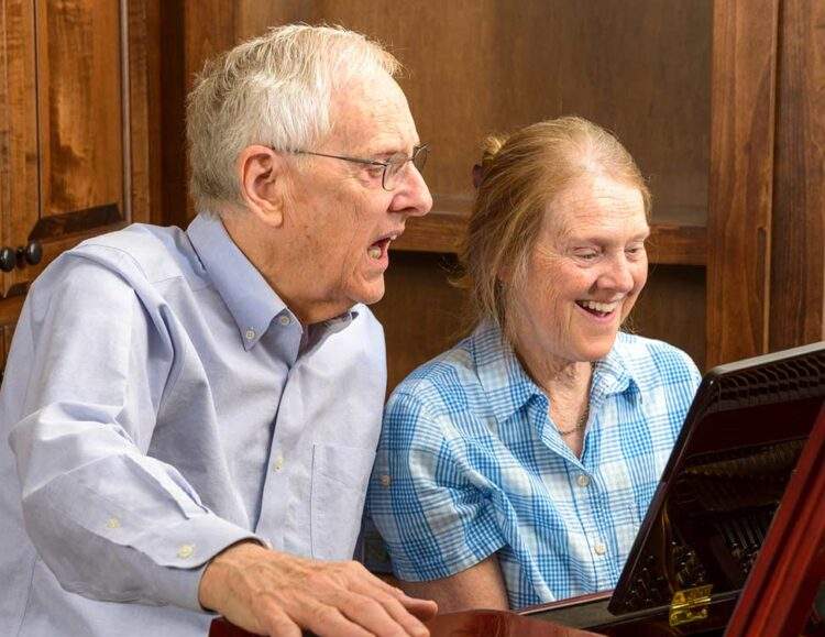 A senior couple play the piano and sing