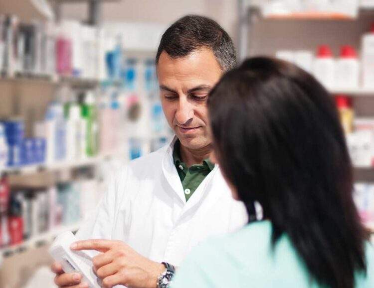 A pharmacist shows a pill bottle to a caregiver
