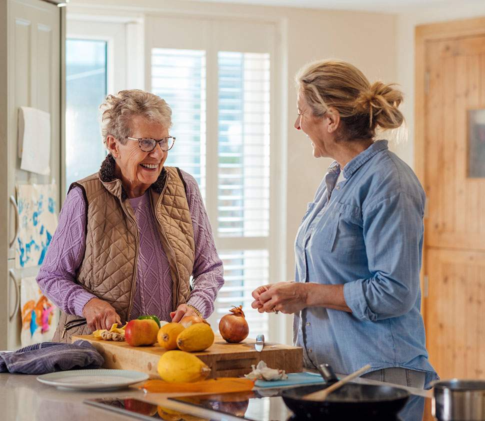 A personal care assistant helps a senior client prepare a meal.