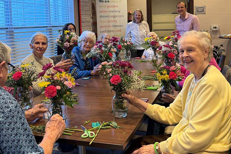 A group of senior citizens gathering to arrange flowers.