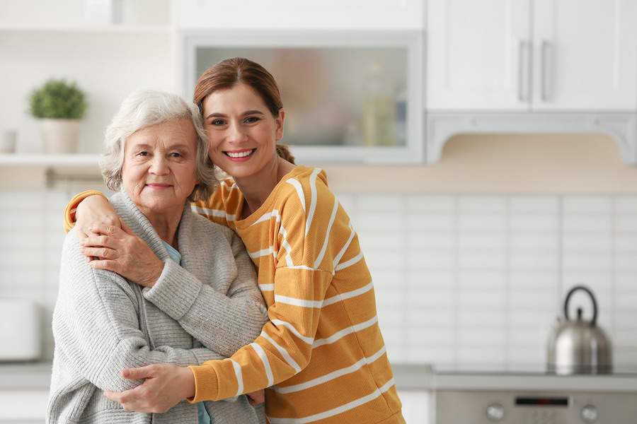 A professional in-home caregiver and an older woman share a laugh together.