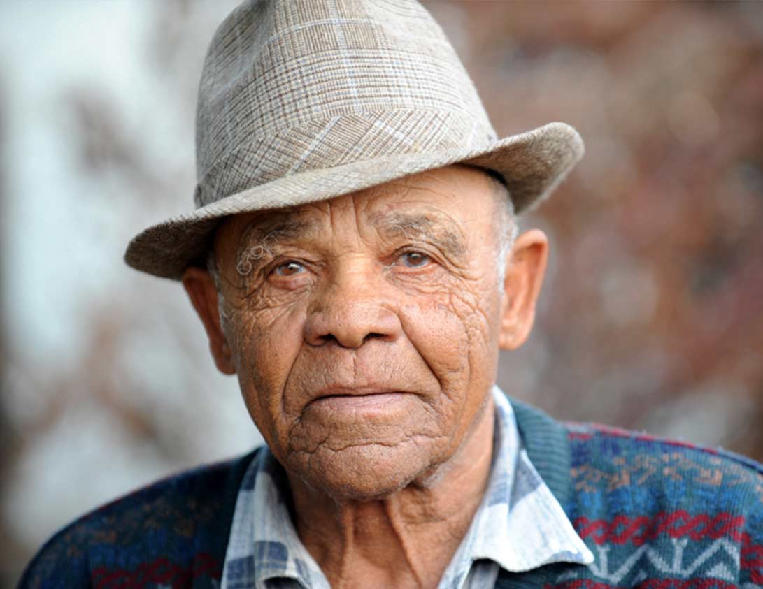 A senior man in a hat and a sweater