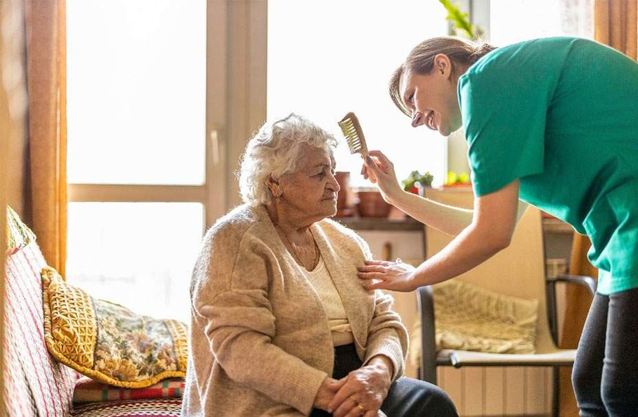 Aid brushing an older woman's hair