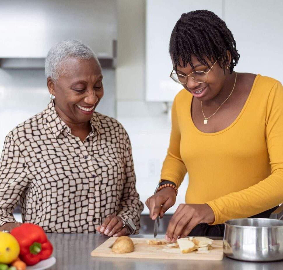 An in-home caregiver assists a senior with cooking.