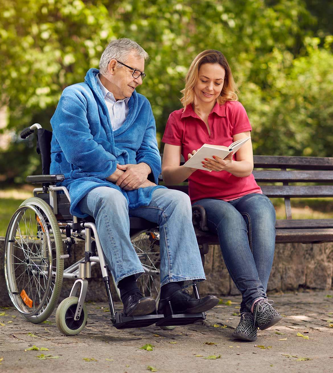 A female caregiver reads to a man in a wheelchair