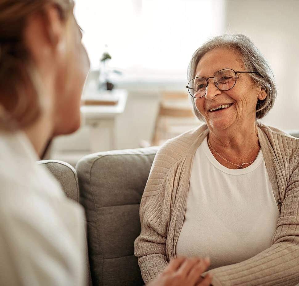 A caregiver sits with a senior client in the client's living room
