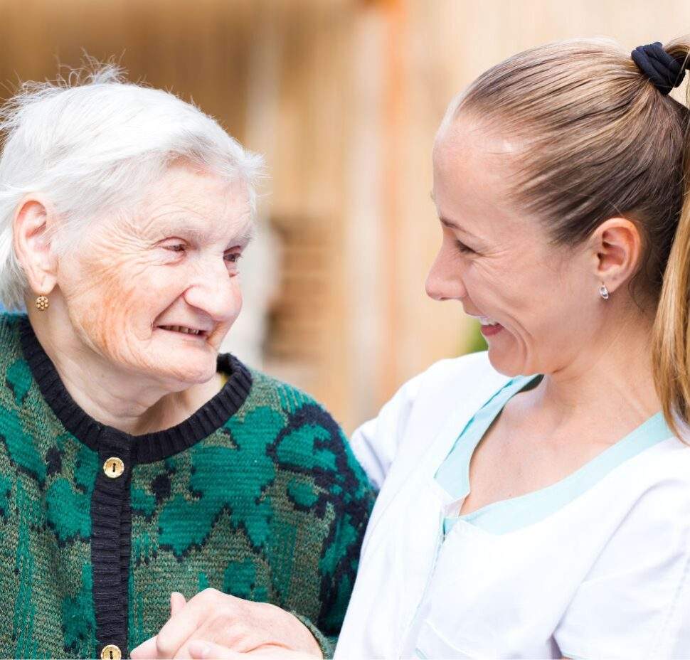 A caregiver sitting next to an elderly woman
