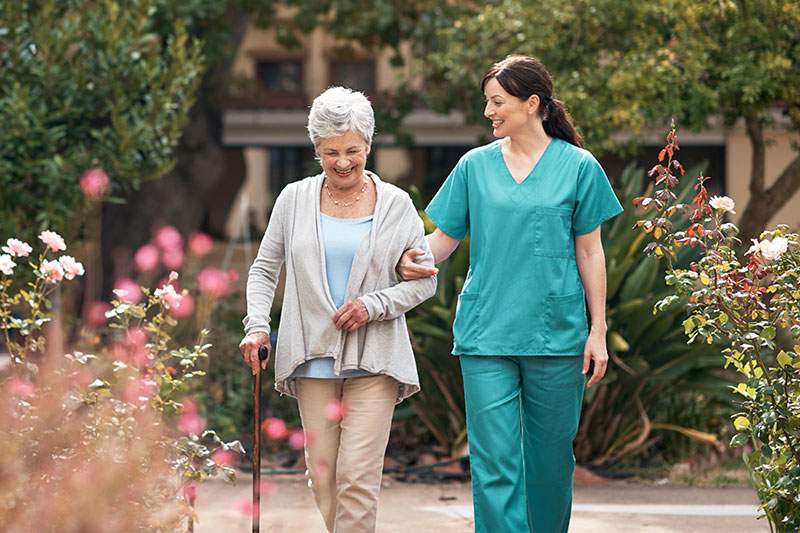 older lady and her caregiver walking through garden
