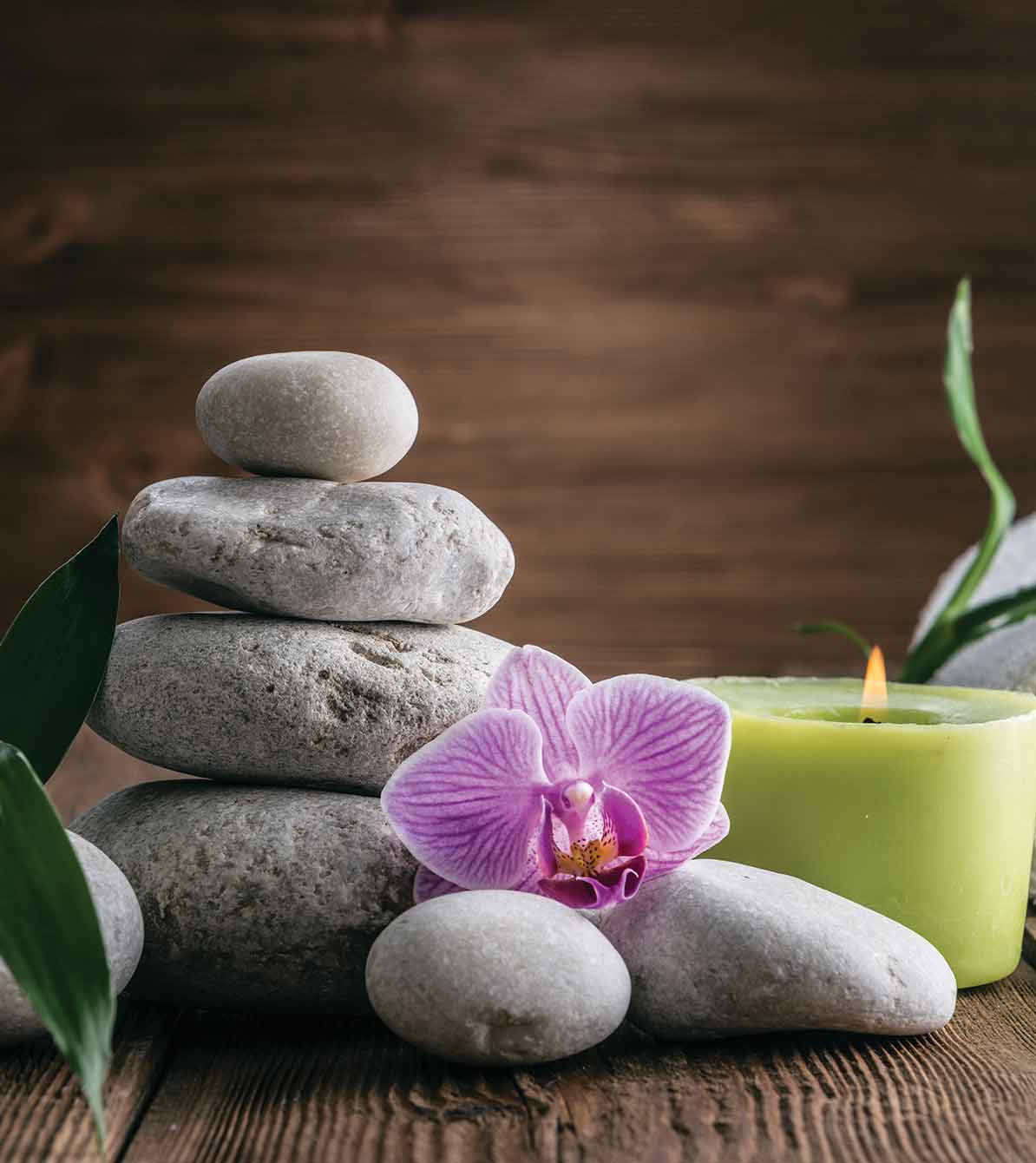 An orchid next to stacked healing stones