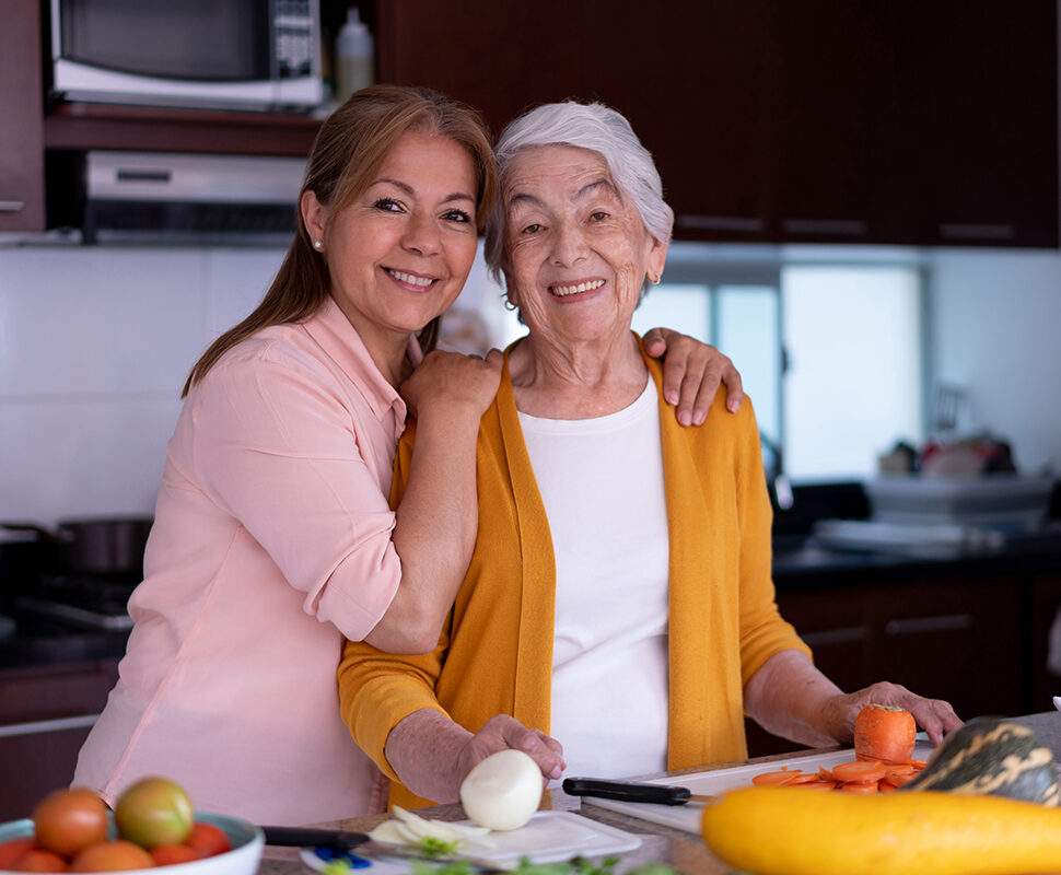 happy adult daughter with her aging mother in the kitchen cooking