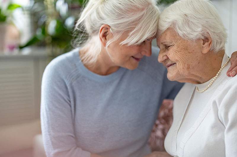 older woman slightly embracing elderly woman