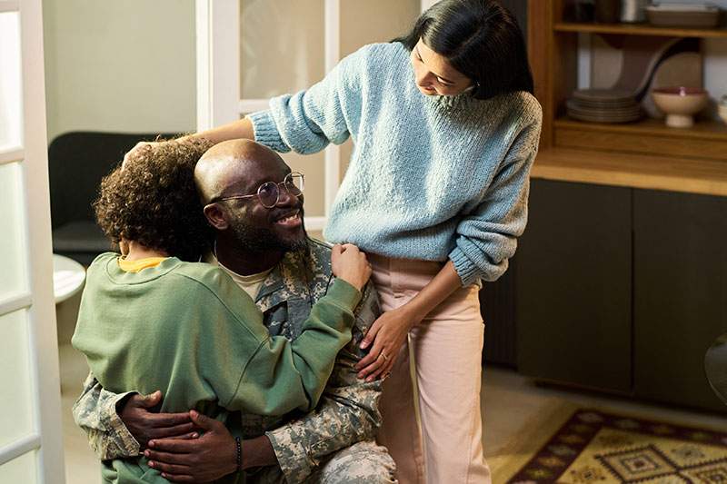A soldier embraces his wife and daughter