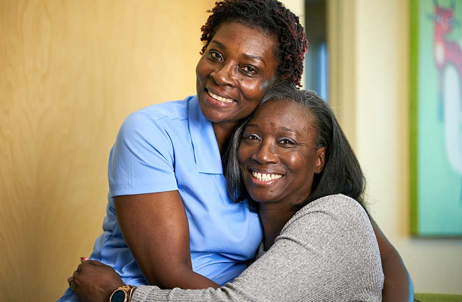 A caregiver hugs the adult daughter of one of her clients