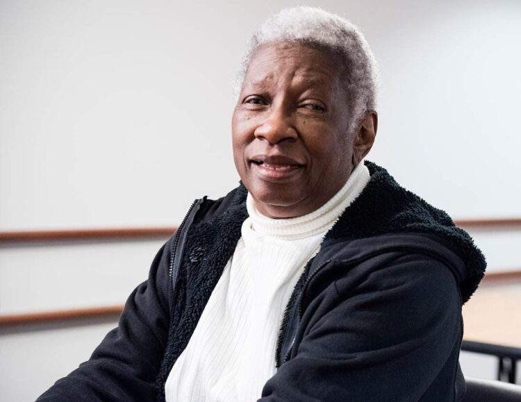 Senior black woman sits and smiles
