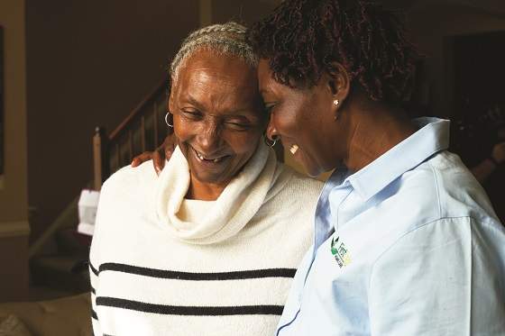 Caregiver smiles whiling giving female client a hug