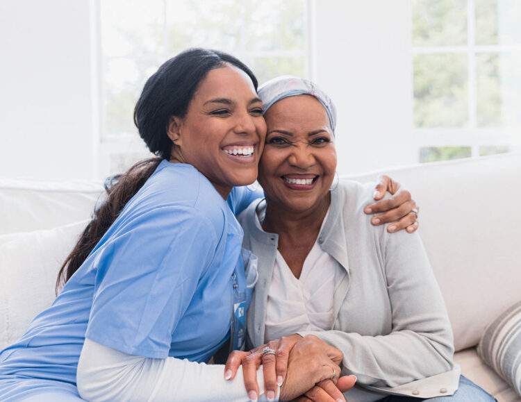 A caregiver sites with a client and gives her a hug