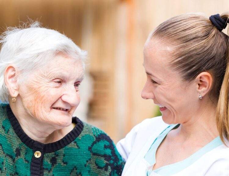 A caregiver sitting next to an elderly woman