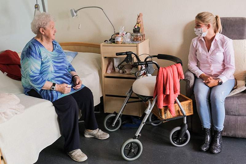 elder person on the bed and care giver sitting nearby