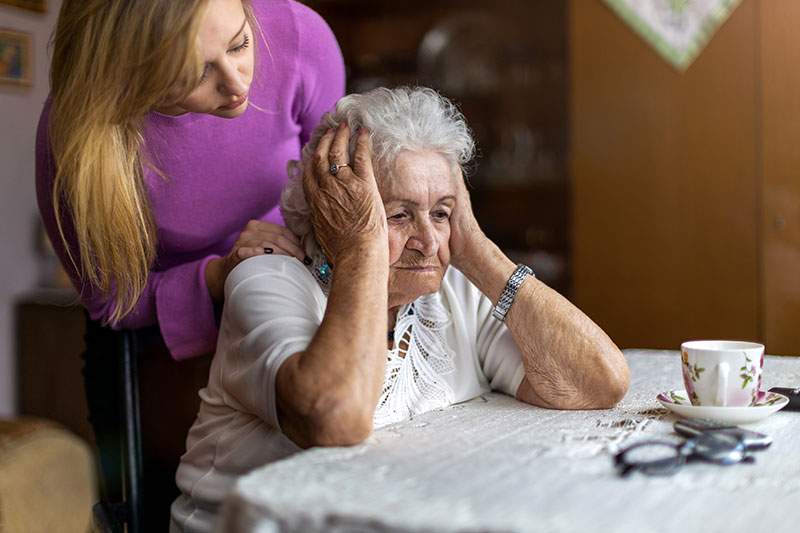 older woman with her hands on her head and wyounger woman over her