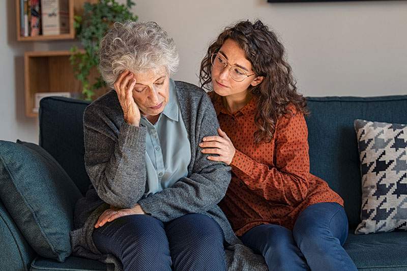 older woman with her hand on head and younger woman beside her