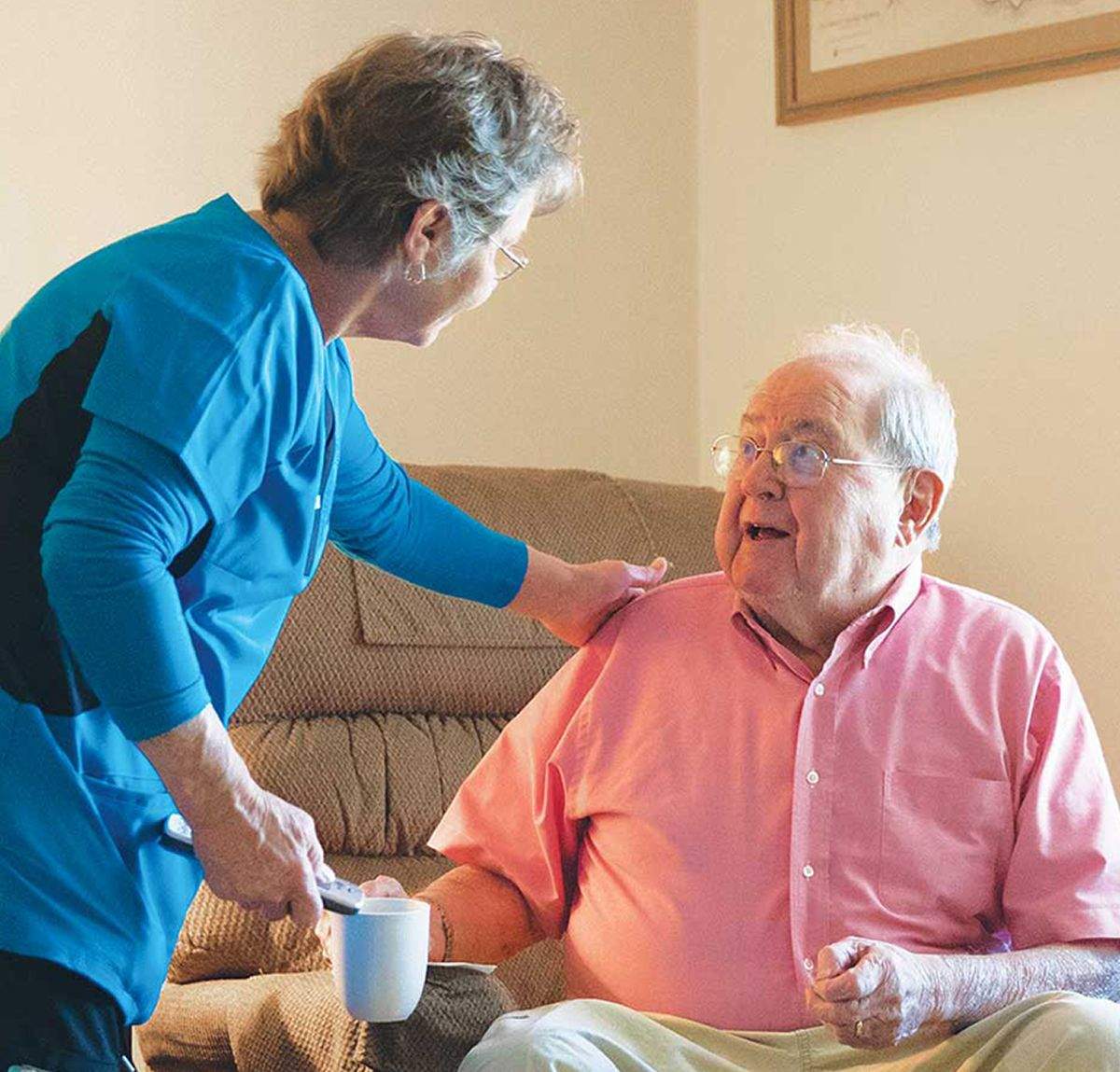 FirstLight Caregiver of the Year, Debbie, leans over to speak to a seated client