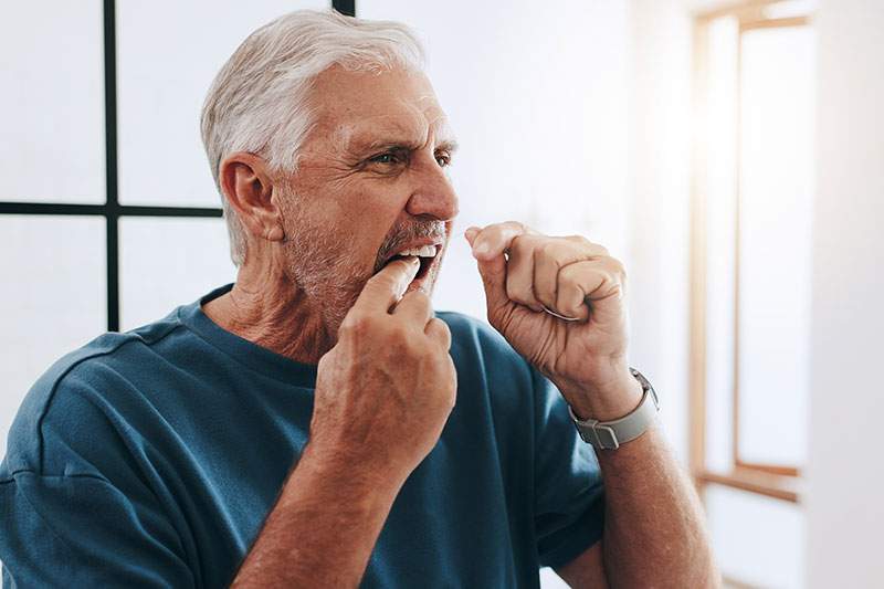 An older man flossing