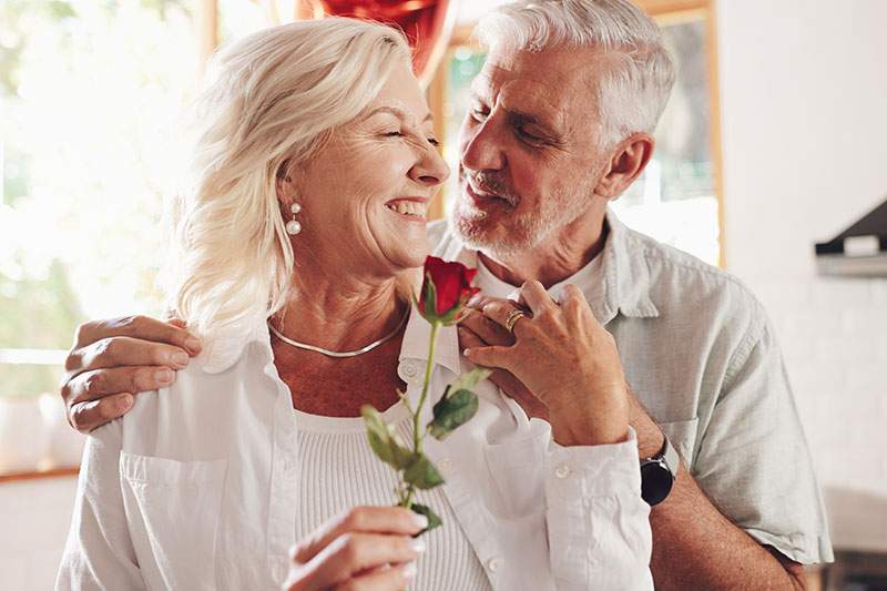 man hugging a woman with a rose in her hand