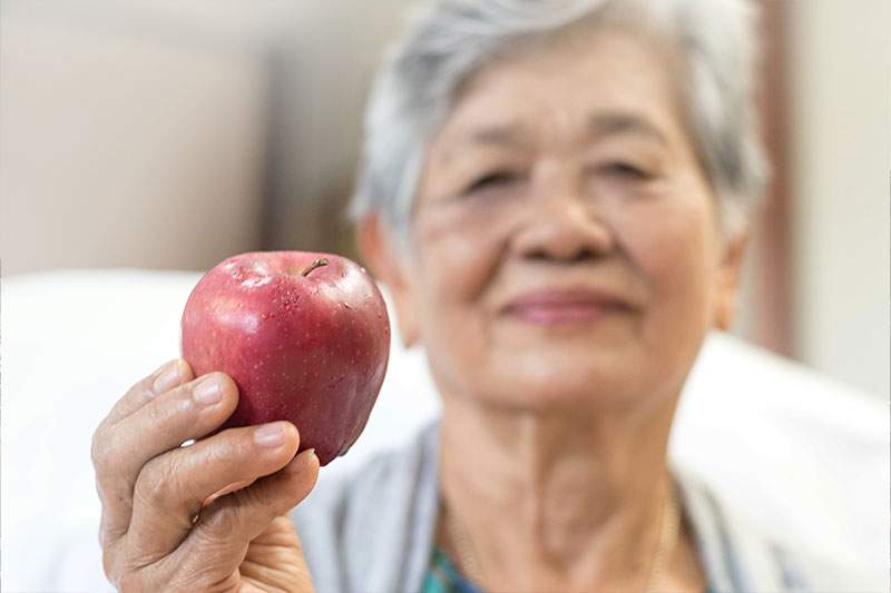 older woman holding an apple